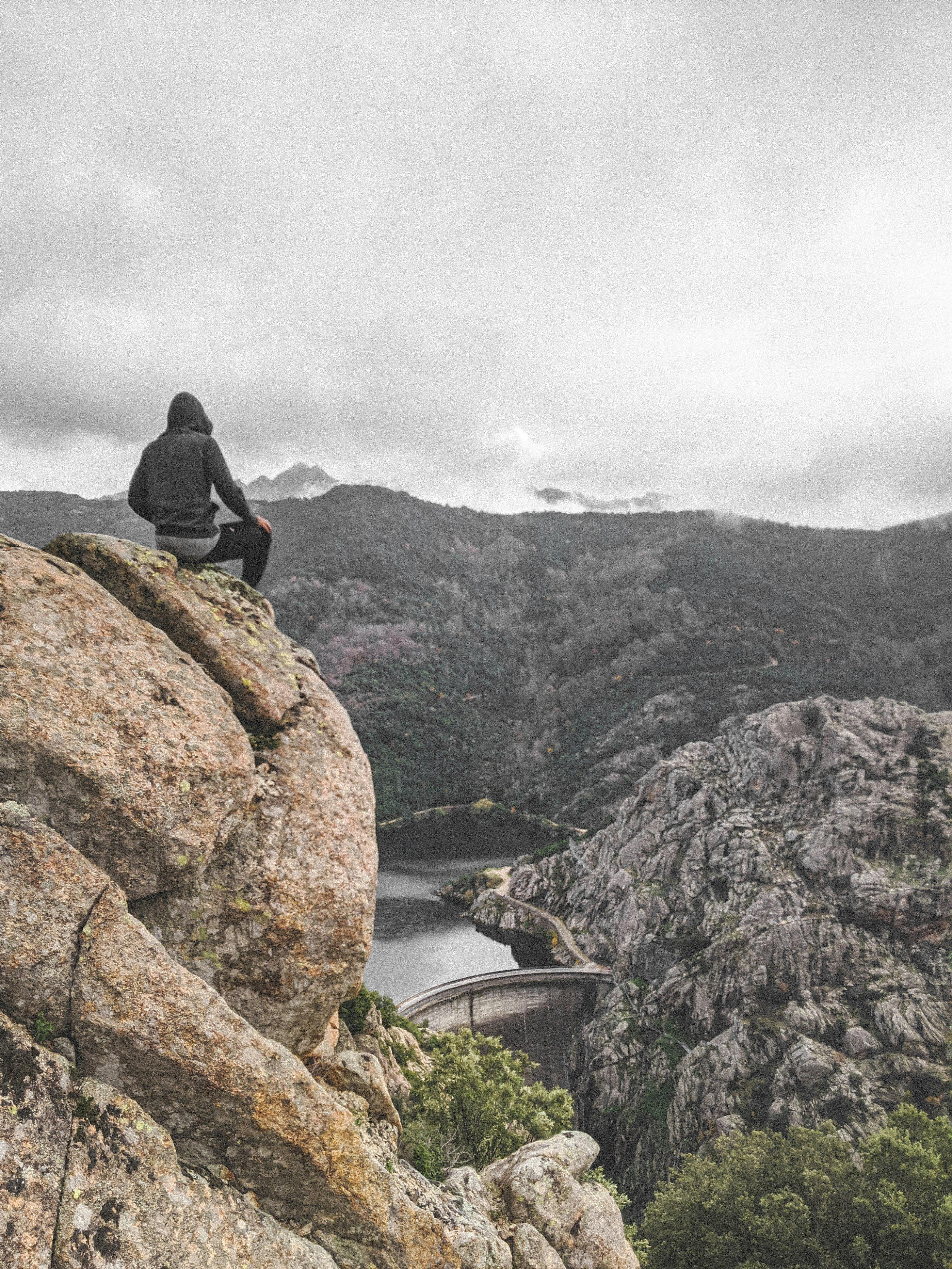 person wearing gray pullover sitting on mountain edge